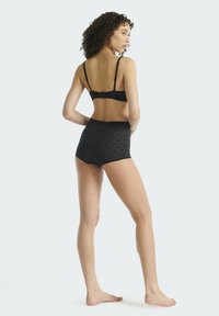 Zwarte lingerieset bestaande uit een bralette met verstelbare bandjes en een taillebroekje met een gestructureerd patroon, gezien van achteren.