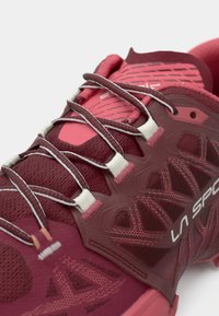 Tuvuma skats maronu un rozā La Sportiva skriešanas apaviem ar detalizētu šņorēšanu un acs auduma augšdaļu.