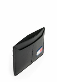 Portafoglio in pelle nera con superficie testurizzata, dotato di due fessure per carte e un logo Tommy Jeans in blu, rosso e bianco sulla parte anteriore.