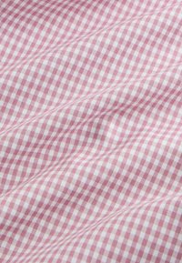 Tessuto a quadretti rosso e bianco con una texture liscia, caratterizzato da piccoli motivi a scacchiera su tutta la superficie, disposto in modo drappeggiato.