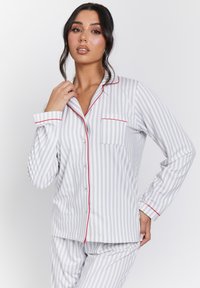 Grey and white striped pajama set with red piping, featuring a button-up shirt, long sleeves, and a breast pocket detail. Soft fabric texture.