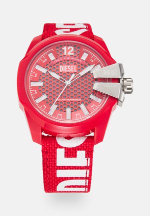 Rote solarbetriebene Uhr mit einem hexagonal gemusterten Ziffernblatt, leuchtenden Stundenmarkierungen und einem strukturierten, roten Stoffarmband mit weißem Branding.