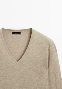 Beige V-Ausschnitt-Pullover mit weicher Textur und lässiger Passform, mit dem Markenlabel "Massimo Dutti" am Kragen.