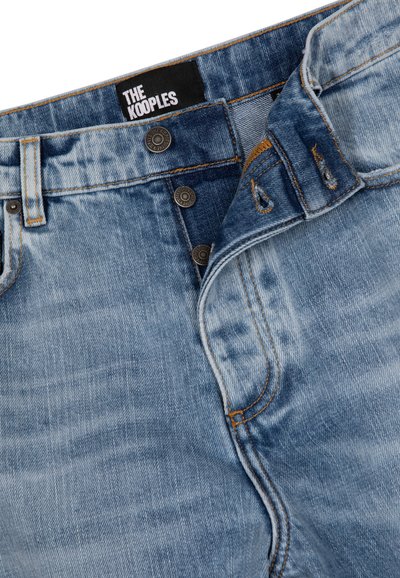 Lichtblauwe denim jeans met gedeeltelijk open knoopsluiting, contrasterende oranje stiksels en een zwart label met de tekst "THE KOOPLES" op de tailleband.