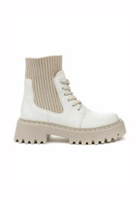 White leather ankle boots with beige ribbed knit sock upper, rounded toe, and chunky patterned sole. Features laces and side panels.