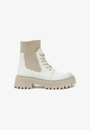 Weiße Leder-Stiefeletten mit beigem geripptem Strickobermaterial, runder Zehenpartie und klobiger, gemusterter Sohle. Verfügt über Schnürsenkel und Seitenpaneele.