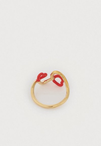 Χρυσό δαχτυλίδι με λείο, καμπυλωτό σχέδιο, με δύο κόκκινες λεπτομέρειες στην ανοικτή πλευρά. Μινιμαλιστικό και μοντέρνο στυλ.