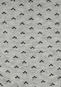 Szary materiał z powtarzającym się czarnym wzorem nietoperzy. Struktura wydaje się dzianinowa, z małymi, równomiernie rozmieszczonymi kształtami nietoperzy na całej powierzchni.