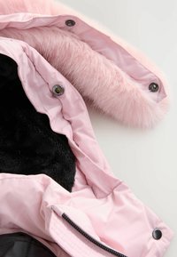 Giacca rosa chiaro con cappuccio in pelliccia sintetica e fodera interna nera. Presenta bottoni a pressione e una chiusura con zip sul davanti.
