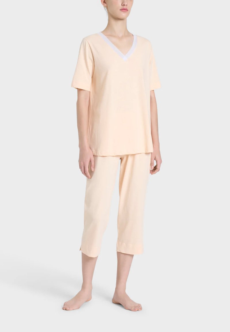 Completo loungewear color pesco con top a maniche corte e scollo a V con bordi bianchi e pantaloni corti. Tessuto morbido e leggero; vestibilità comoda.