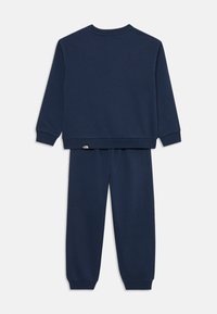 Marinblå sweatshirt och byxset i mjukt tyg, med ribbade muddar och midja. Litet logodetalj på byxorna.