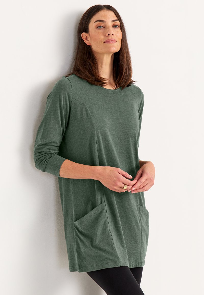 Langärmlige Tunika aus dunklem grünem Baumwollgemisch, mit rundem Halsausschnitt, lässigem Schnitt und zwei Seitentaschen. Glatte Textur und leichtes Design.