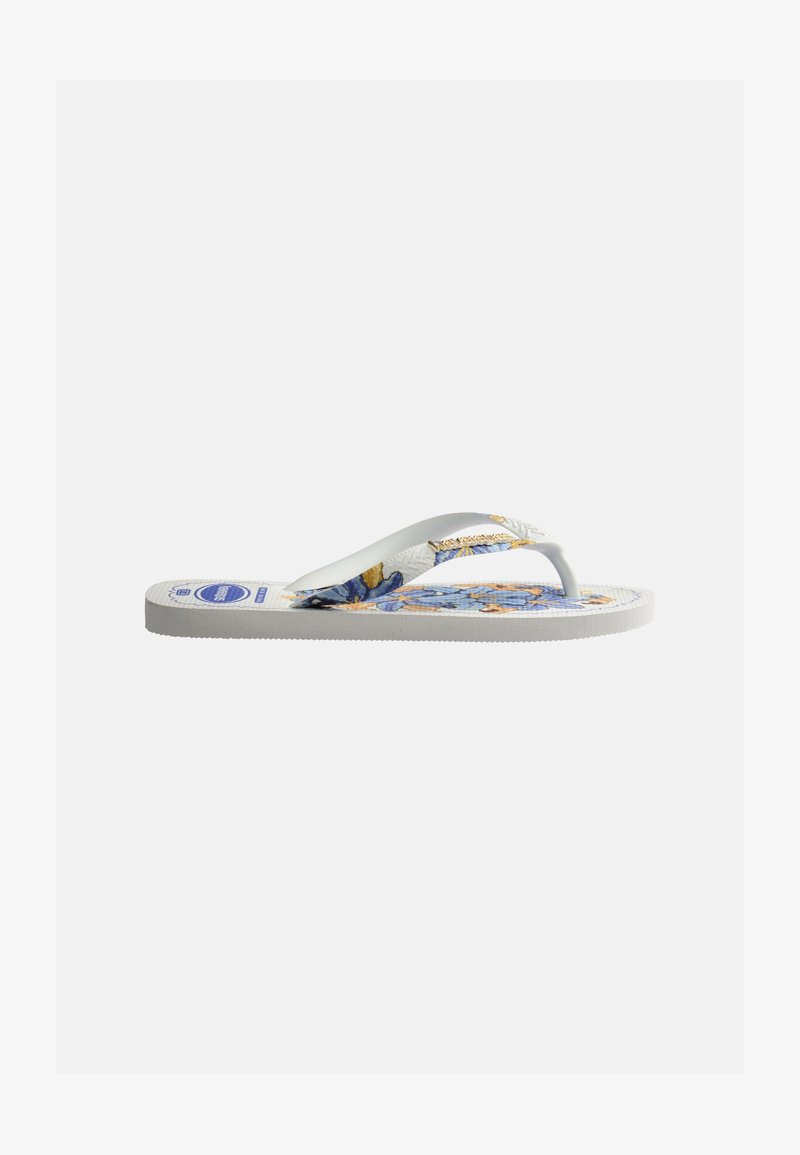 Λευκή παντόφλα τύπου σαγιονάρα με μπλε φλοράλ σχέδιο στη σόλα και λευκές υφασμένες λουρίδες, εμφανιζόμενη από το πλευρό σε απλό φόντο.