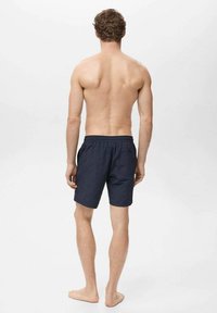 Shorts de bain bleu marine avec une taille élastique et des poches latérales, fabriqués en tissu léger, dotés d'un design uni et d'une coupe décontractée.