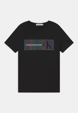 Czarny bawełniany t-shirt z prostokątną grafiką z napisem "CALVIN KLEIN JEANS" oraz metalicznym gradientowym akcentem. Okrągły dekolt, krótkie rękawy.