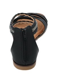 Sandal nera con chiusura a zip, accentata da una fascia intrecciata e una suola marrone testurizzata. Presenta un design aperto con una finitura liscia.