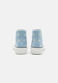 Blå denim högskurna sneakers med vita gummisulor, som har gula broderade solmönster och kontrasterande svarta ränder.