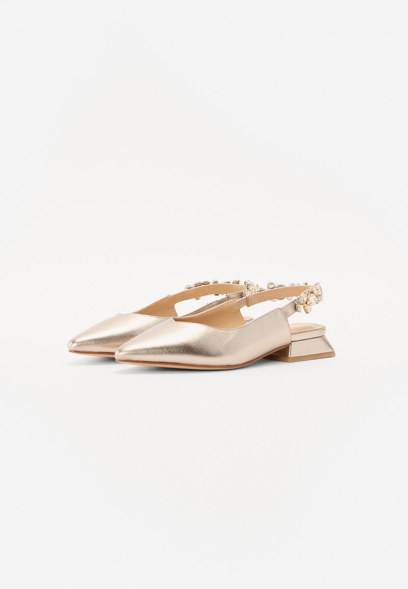 Zapatos slingback de punta en piel metálica dorada. Presenta un bajo tacón geométrico y una hebilla decorativa en la correa. Textura lisa.