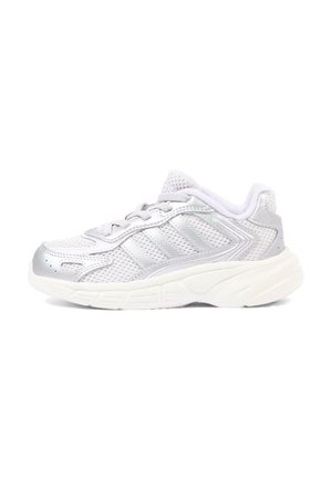 Biało-srebrny sportowy sneaker z siateczkową cholewką, sznurowanym designem i grubą amortyzowaną podeszwą, widziany z boku na białym tle.