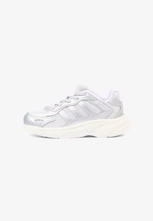Biało-srebrny sportowy sneaker z siateczkową cholewką, sznurowanym designem i grubą amortyzowaną podeszwą, widziany z boku na białym tle.
