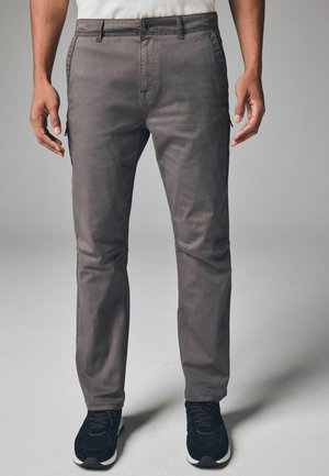 Graue Baumwollhose mit schmaler Passform, ausgestattet mit vorderen Taschen und einer mit Reißverschluss versehenen Seitentasche. Schmale Beinform und leicht strukturierter Stoff.