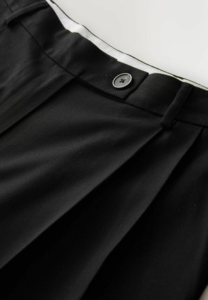 Black pleated trousers featuring a button closure at the waist, made of textured fabric with a smooth inner lining and tailored finish.