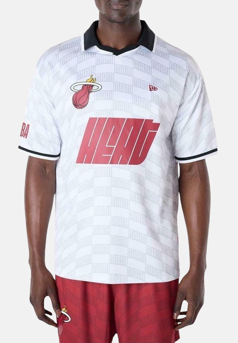 Witte jersey met een textuurpatroon, zwarte kraag, rood "HEAT" logo en Miami-embleem. Korte mouwen met zwarte accenten.