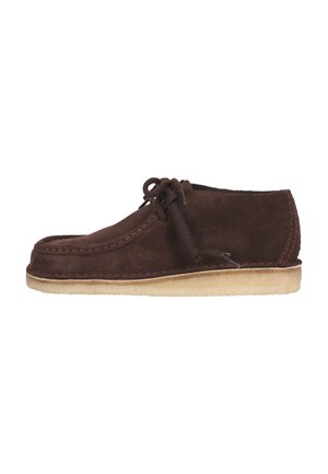 Chaussure en daim marron avec un bout rond, un design à lacets, des coutures beige et une semelle en caoutchouc légèrement texturée.