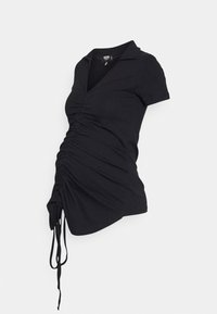 Top de maternidade preto com colarinho tipo polo, mangas curtas e detalhes franzidos na cintura, apresentando laços ajustáveis na bainha.