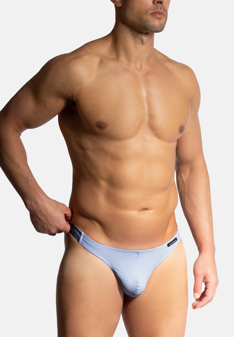 Light blue swim briefs made of smooth material, featuring a low-rise design and a logo tag on the waistband. The model has an athletic build.