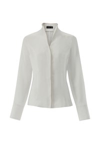 Camicia bianca a maniche lunghe con colletto alto, caratterizzata da un design elegante e un bordo dorato a contrasto lungo l'apertura frontale e i polsini.