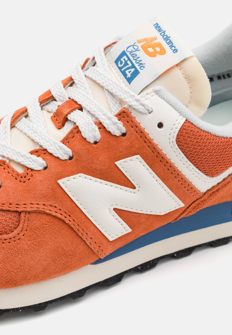 Baskets en suède orange et maille avec des accents en cuir blanc. Présentent des œillets espacés, des lacets blancs et une semelle intermédiaire bleue. Style classique avec un détail de logo.