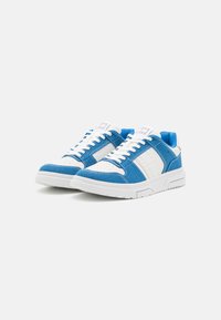 Sneaker blu e bianchi con tomaia in tessuto testurizzato, punta forata e suola in gomma solida. Presentano dettagli cuciti e una linguetta imbottita.