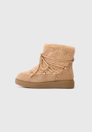 Botas de tobillo color tan con un upper texturizado y lujoso, cordones y herrajes en tono dorado, suela de goma y tachuelas decorativas en el lateral.