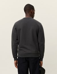 Σκούρο γκρι φούτερ με στρογγυλή λαιμόκοψη, ραμμένα μανίκια και τελείωμα. Μαλακό, υφασμάτινο υλικό; απλός σχεδιασμός χωρίς ορατά λογότυπα ή μοτίβα.