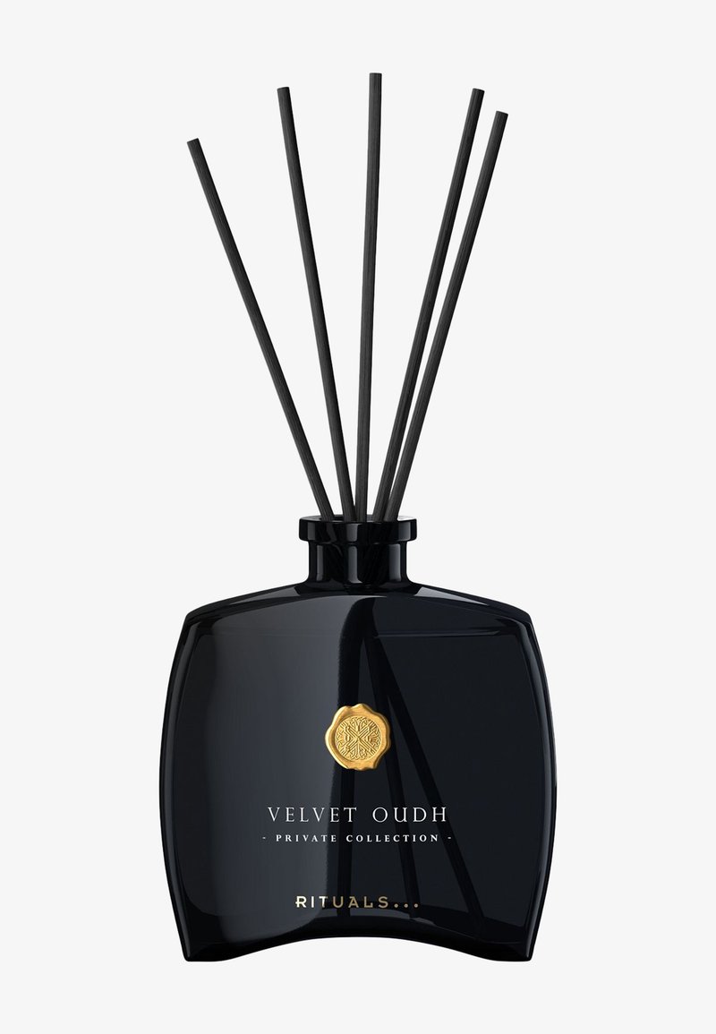 Diffusore in vetro nero con cinque canne nere, emblema dorato e testo "Velvet Oudh - Collezione Privata - Rituals" sul davanti.