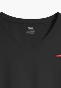 Black V-neck T-shirt made of cotton, featuring a small red Levi's logo on the left side near the hem, and a textured neckline.