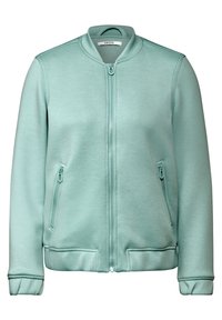 Světle zelená zipová bunda s jemným límcem, zapínacími bočními kapsami a elastickými manžetami, značková etiketa "CECIL" uvnitř límce.