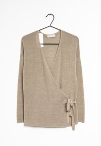 Beżowy sweter typu wrap z długimi rękawami, głębokim dekoltem w kształcie litery V oraz szczegółowym węzłem z boku. Dzianinowa faktura z subtelnymi metalicznymi nitkami w całej powierzchni.