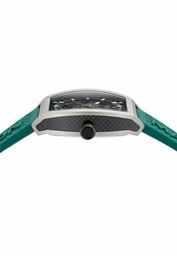 Taisnstūra pulkstenis ar nerūsējošā tērauda korpusu, melnu oglekļa šķiedras akcentu un zaļu gumijas siksniņu ar teksturētu apdari. Melns pulksteņa ciparnīca ar sudraba marķieriem.