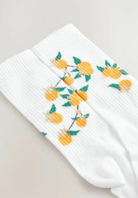 Hvide ribbede sokker med broderede gule citrusfrugter og grønne blade, samt et blomstermønster langs siden.