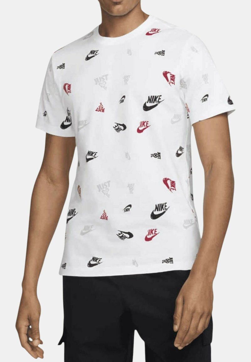 T-shirt bianca in cotone con vari loghi Nike in rosso, nero e grigio. Maniche corte e design a girocollo.