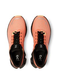 Coral running shoes with a breathable mesh upper, black laces, padded collar, and cushioned black sole, featuring logo details on the tongue.