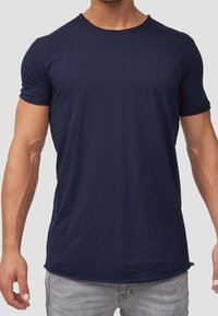 T-shirt blu navy a maniche corte con col rotondo, realizzato in un tessuto morbido, con un orlo leggermente curvo e dettagli minimi.
