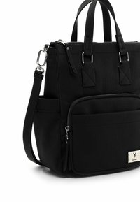 Black fabric handbag with vertical ribbed texture, two short handles, adjustable strap, silver hardware, front zipper pocket, and logo patch.