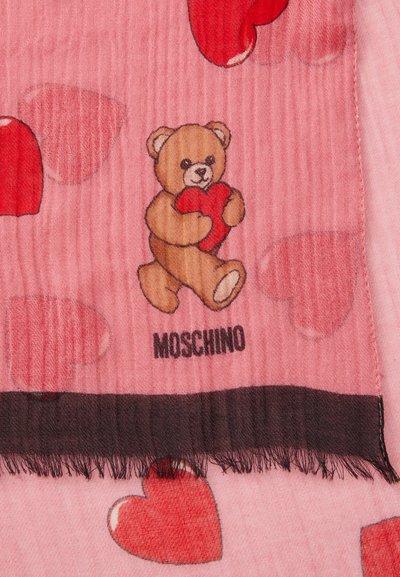 Gaiši rozā šalle ar lāci, kas tur sarkanu sirdi, izkliedētiem sarkanu sirdīm un melnu pūkainu apmalīti. Zīmols: Moschino.