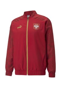 Czerwona nylonowa kurtka z złotym zamkiem, z teksturowanym wzorem na rękawach i logo herbu na klatce piersiowej. Regulowane mankiety i dół.