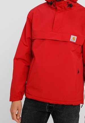 Red waterproof pullover jacket with a high collar, front pocket, and adjustable hood. Features a logo patch and elastic cuffs.