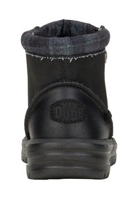 Botín negro hasta el tobillo con un exterior de cuero texturizado y un suave forro de felpa gris. Presenta un parche con el logo y una suela de goma resistente.