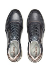 Zapatos de cuero azul oscuro con un acabado suave, con punteras redondeadas, costuras en marrón en contraste y un cierre lateral con cremallera. Suelas de goma blancas.